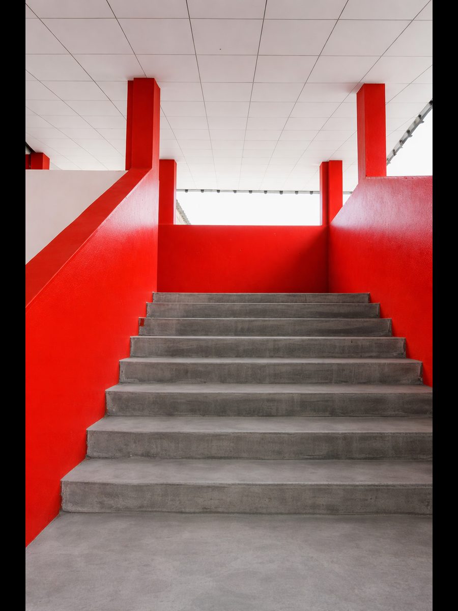 Escalier du campus OKHI — architecture rouge et béton